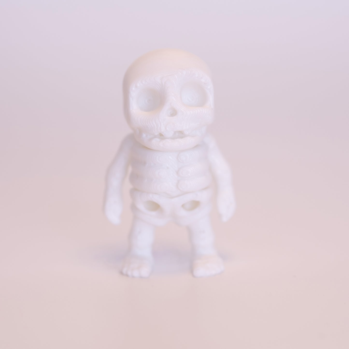 A 3D printed all white Skeleton figurine, standing on an off white background.