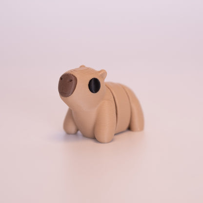 A 3D Printed Capybara figurine standing on its 4 legs on an off white background. The Capybara is mostly tan with round black eyes, and a brown nose. 