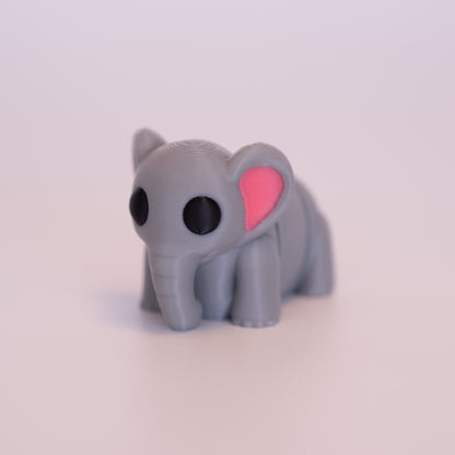 A 3D Printed Elephant figurine standing on its 4 legs on an off white background. The Elephant is mostly grey with round black eyes, and pink accents in the inner ears. 