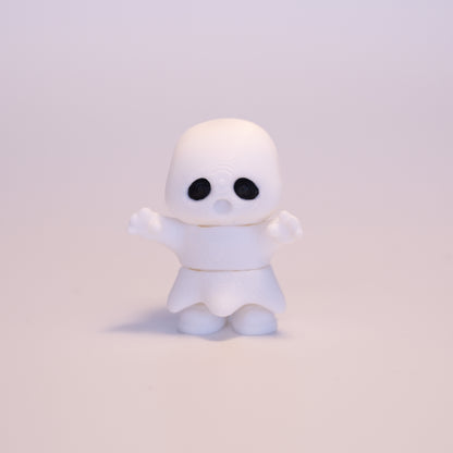 A 3D printed standing Ghost figurine with its hands up on an off white background. The Ghost is almost entirely white with an exception for black eyes.