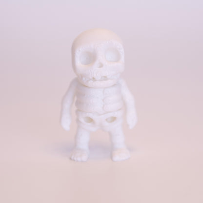 A 3D printed all white Skeleton figurine, standing on an off white background.